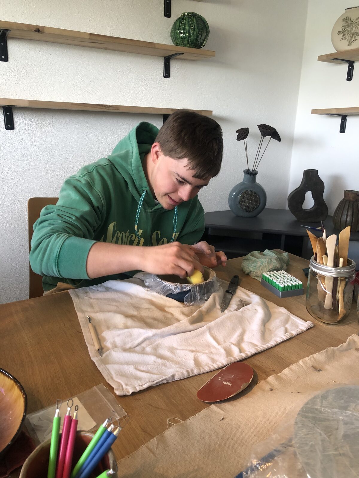 Junger Töpferer formt eine Schüssel im Atelier